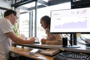 Equipe analisando gráfico de faturamento em um monitor, em um ambiente de escritório